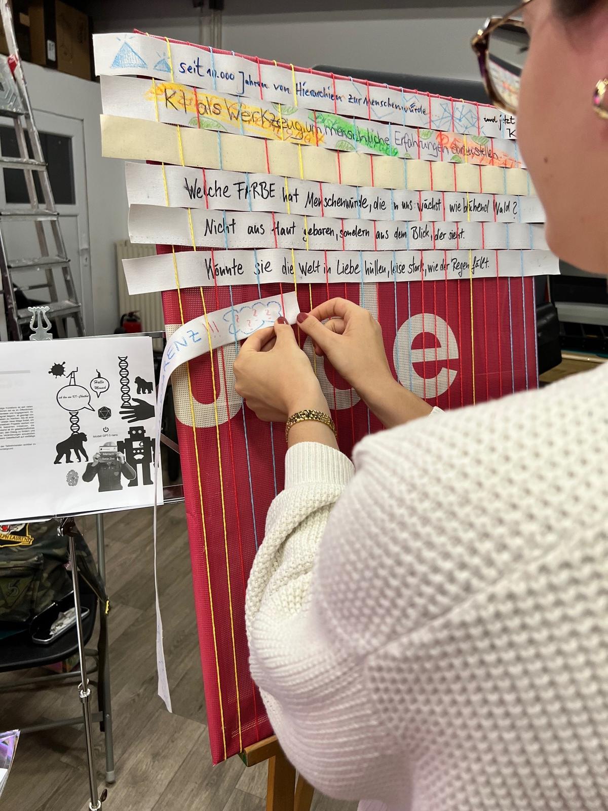 Man sieht im Vordergrund die Schulter und das seitliche Profil einer Frau. Die Frau steht einen Zettel in ein Bild. Darüber wurden schon mehrere Zettel in das Bidl geseteckt.