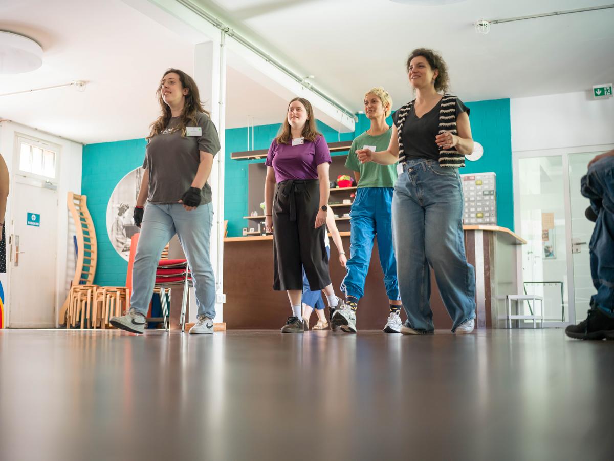 Man sieht vier Frauen, die einen Schritt nach vorne machen und dabei lächeln. 